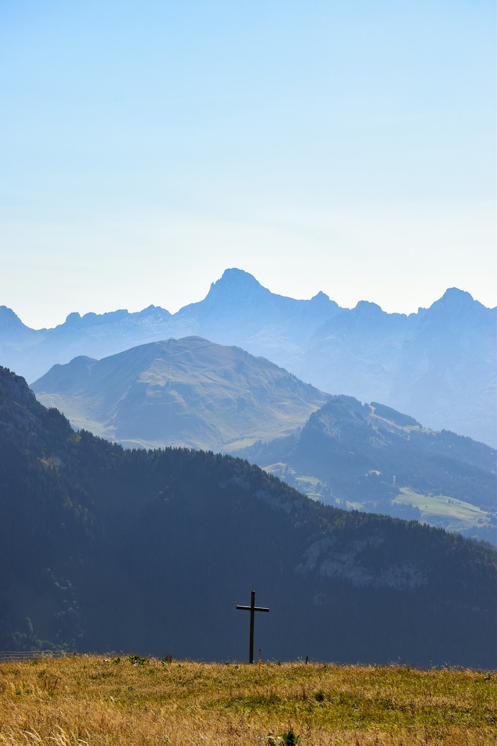 a cross in a field with mountains in the background