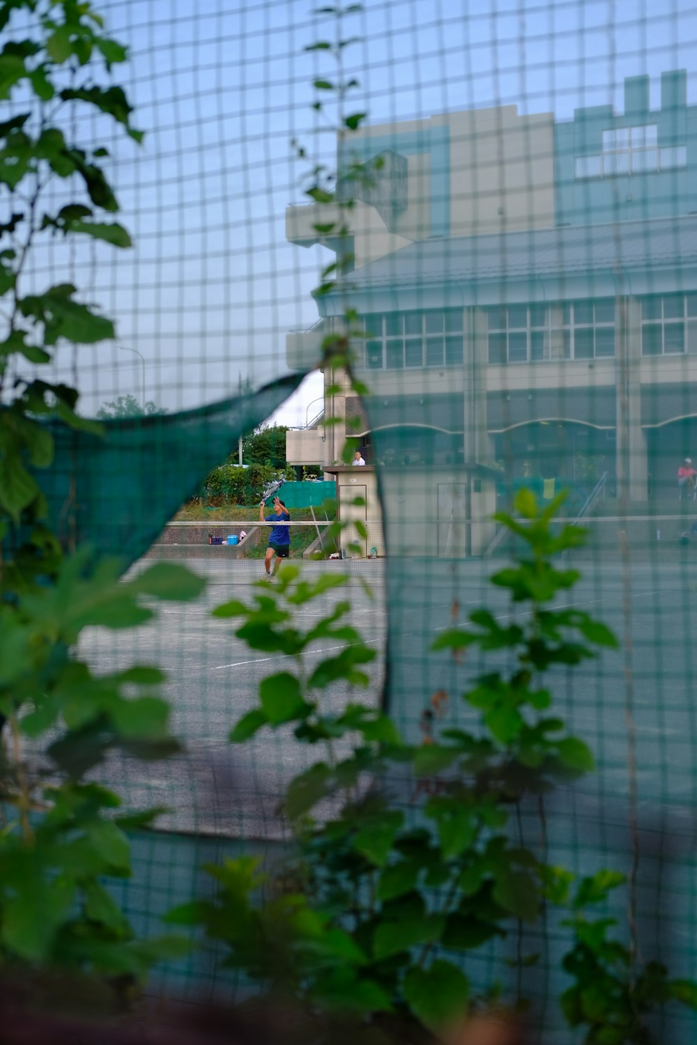 a view of a tennis court through a mesh fence
