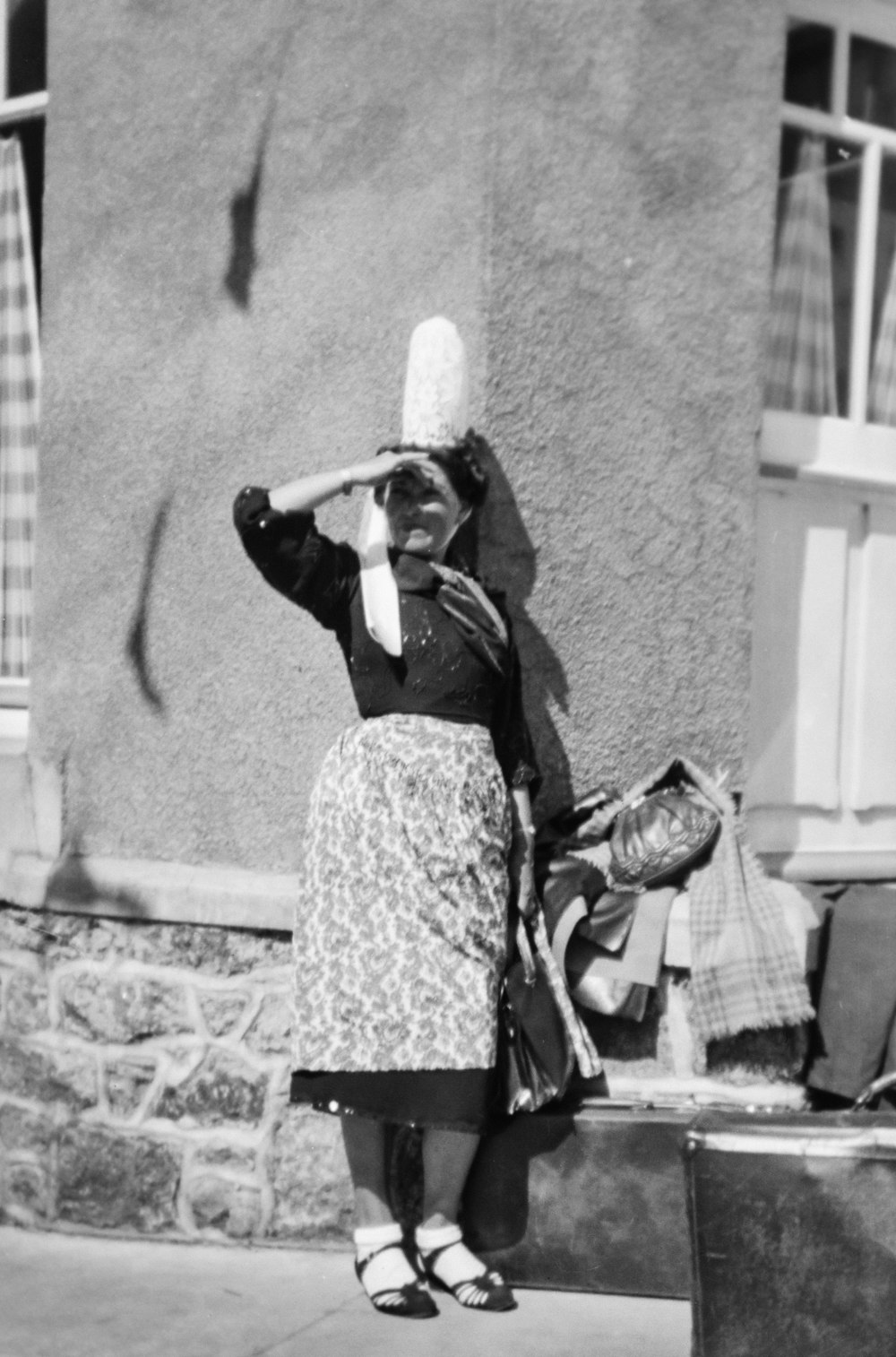 a woman standing on a sidewalk with a hat on her head