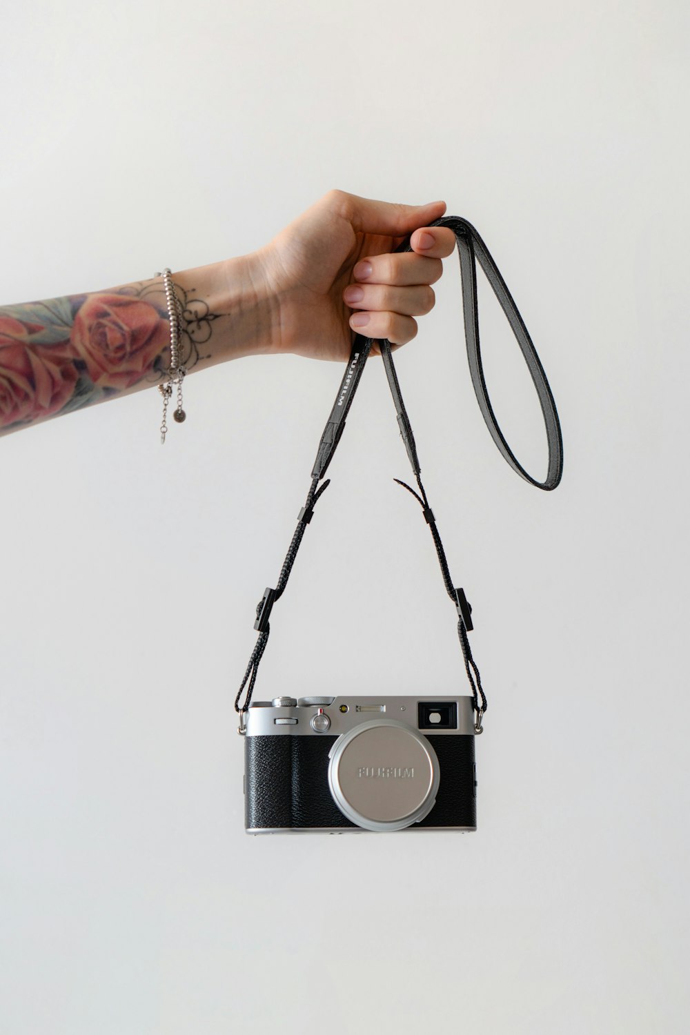 a hand holding a camera with a strap