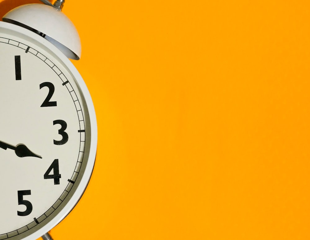 a close up of a clock on a yellow background