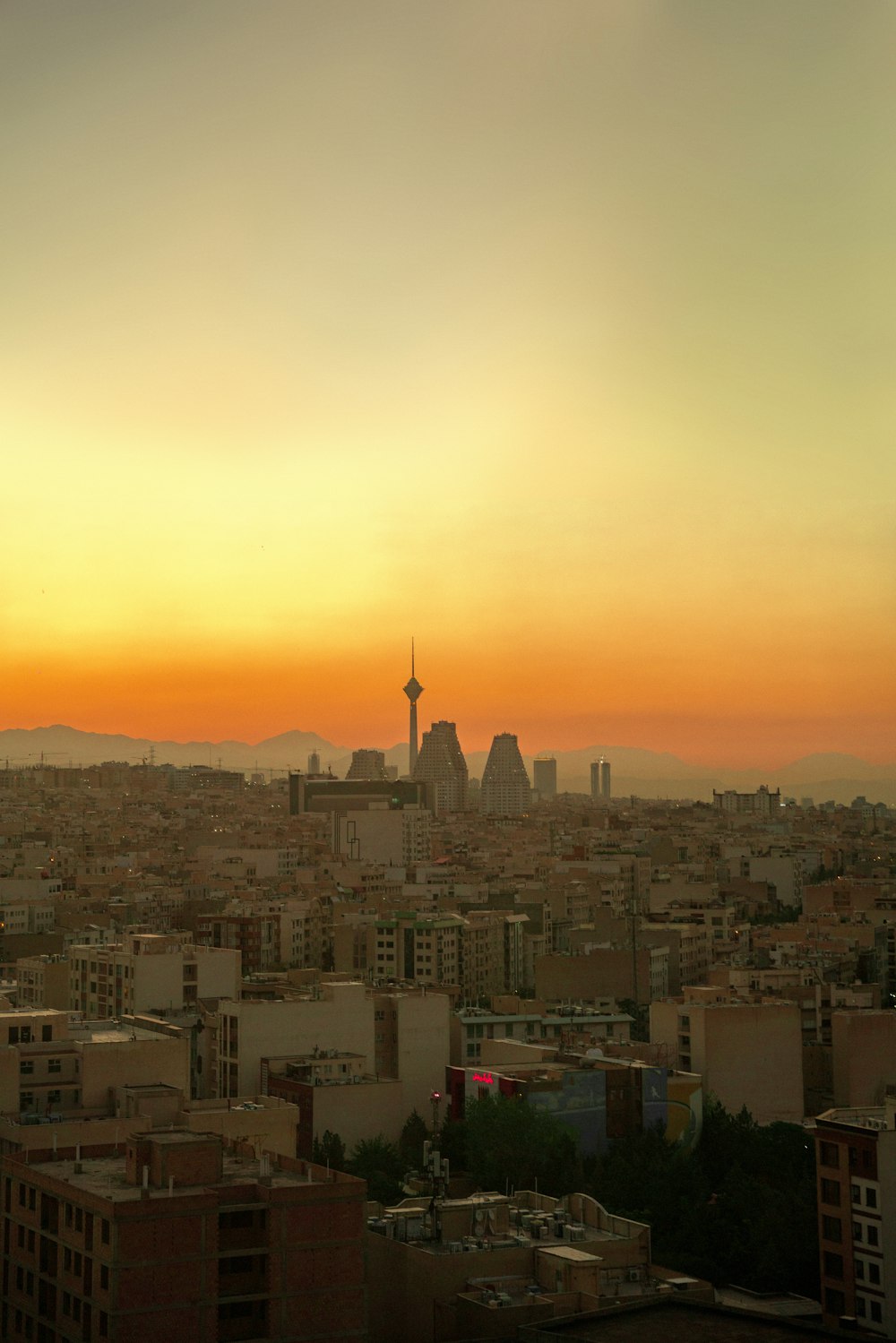 the sun is setting over a city with tall buildings