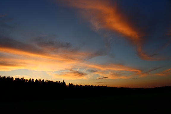 A serene sunset over the lush Ujungkulon National Park with vibrant orange and pink skies.