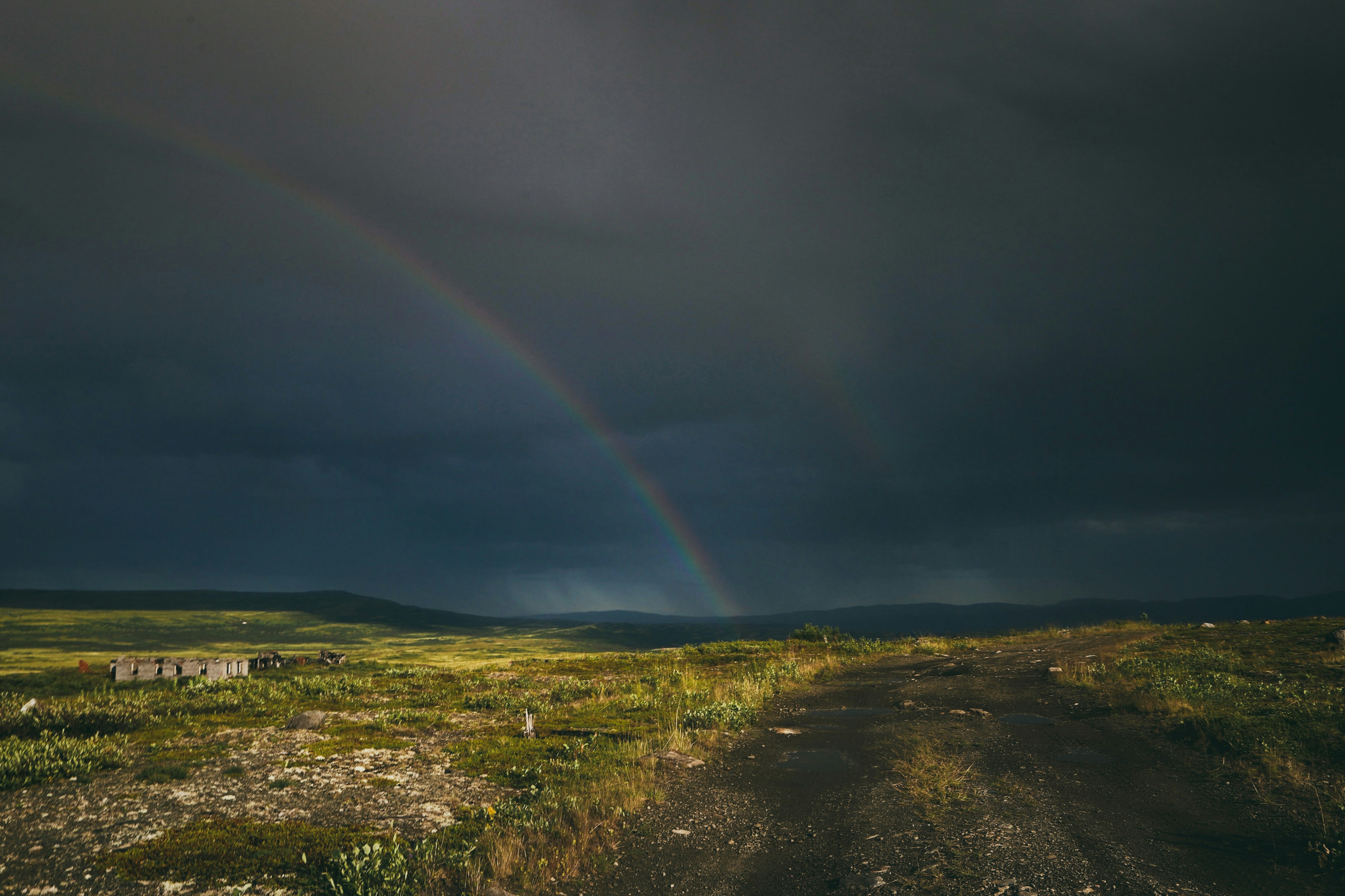 a dirt road with a rainbow in the background