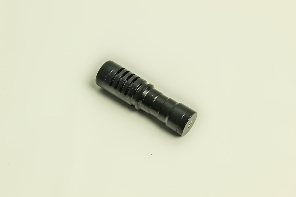 a black flashlight on a white surface