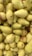 A pile of ripe yellow-green pears with some brown stems visible. The fruits appear fresh and closely packed together, showing a range of light to darker yellow shades with slight red blush on a few.
