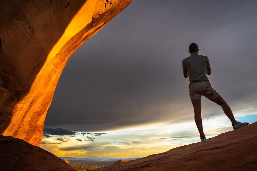 a man standing on top of a desert under a cloudy sky