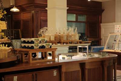 A rustic wooden counter displaying homemade cakes and jars of preserves, with vintage decor in the background.