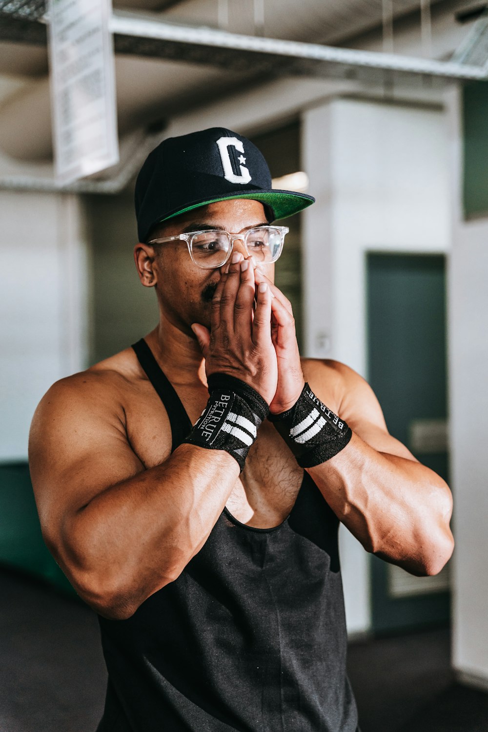 a man in a black tank top and a green hat