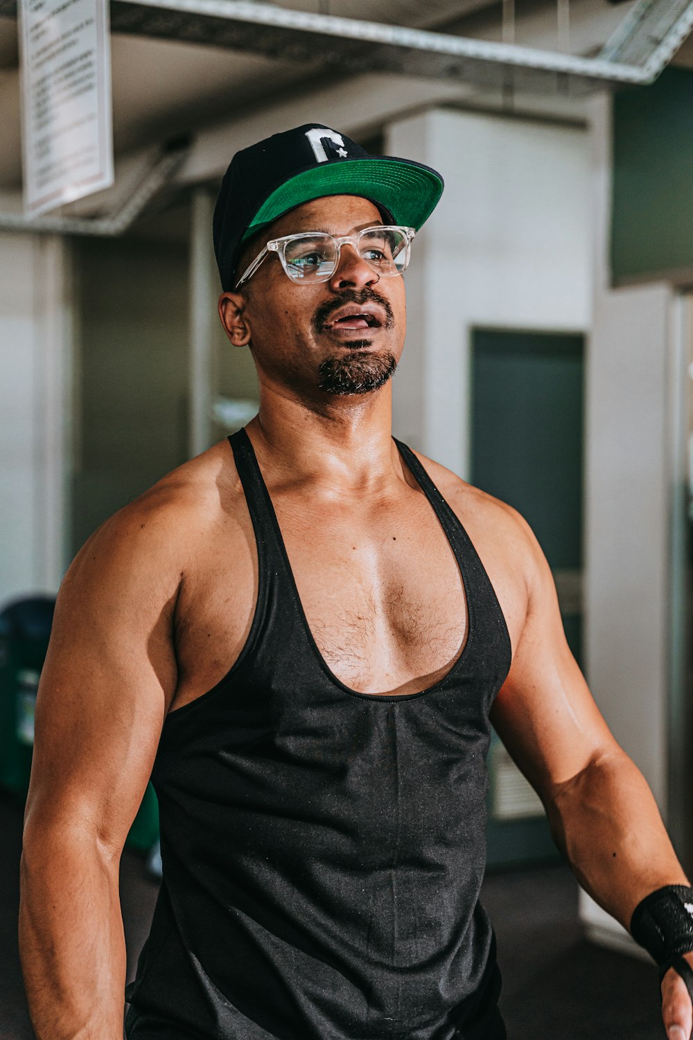 a man in a black tank top and a green hat