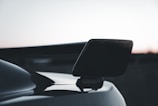 Close-up of a sleek black ABS car spoiler installed on a sporty vehicle under bright sunlight