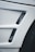 A close-up view of a car's body panel with two vertical rectangular air vents featuring a black mesh pattern, alongside part of a tire visible to the right.