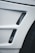 A close-up view of a car's body panel with two vertical rectangular air vents featuring a black mesh pattern, alongside part of a tire visible to the right.