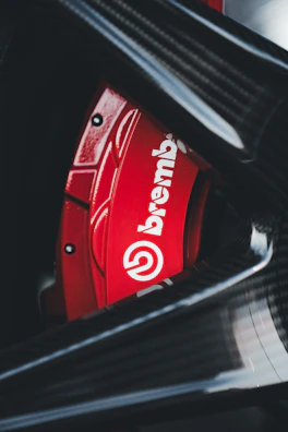 Close-up of the red racing brake caliper against dark industrial background