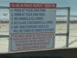 A warning sign lists several rules for a private beach property, detailing regulations such as swimming at your own risk and prohibiting animals and glass containers. The bottom section emphasizes adherence to rules with the potential consequence of being expelled or losing beach privileges.