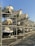 Several motorboats are stored on a large metal rack structure, arranged in rows and stacked vertically. The setting appears to be a marina or boatyard on a sunny day with a clear blue sky.