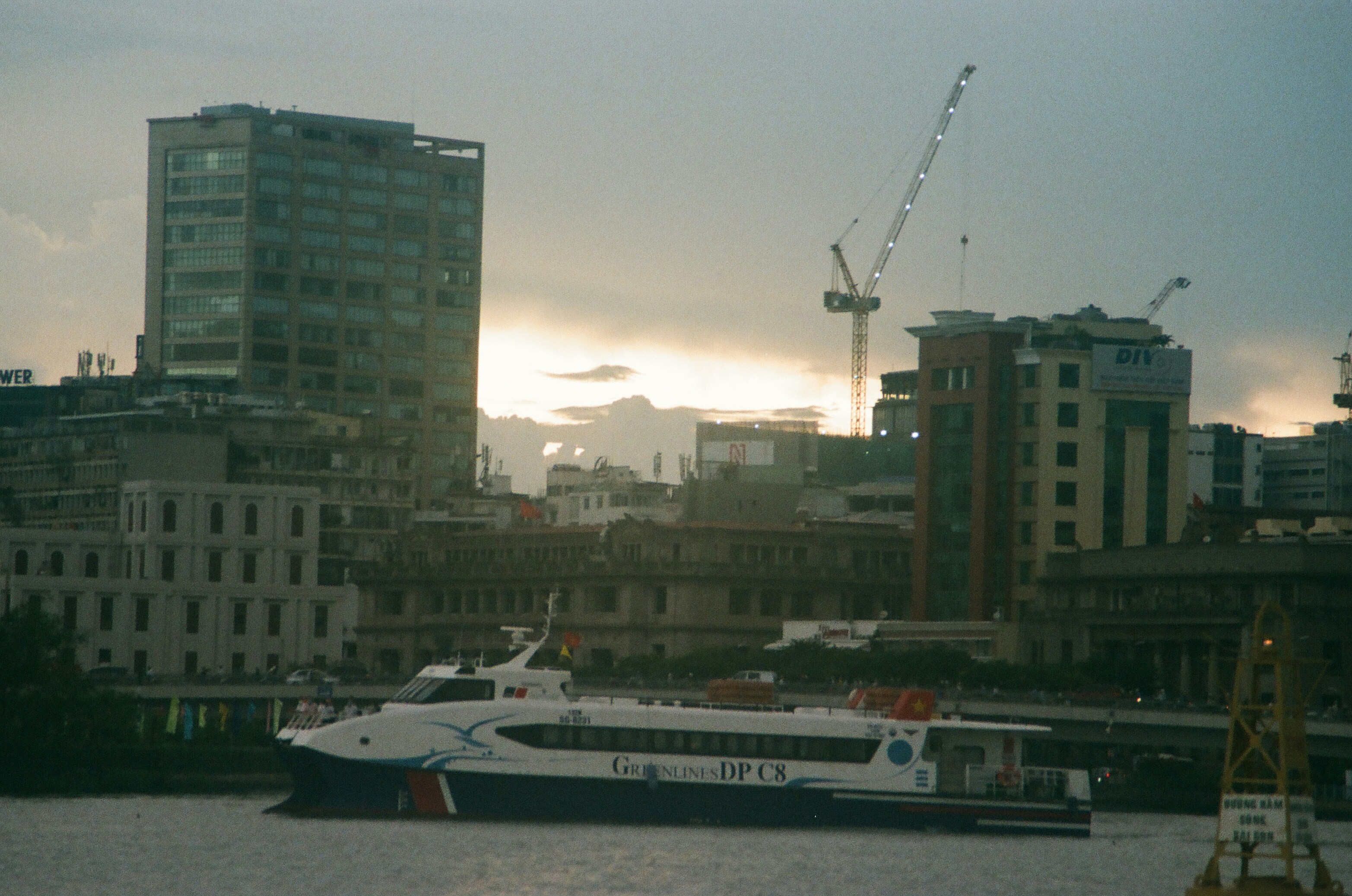 a large boat floating on top of a river next to tall buildings, 