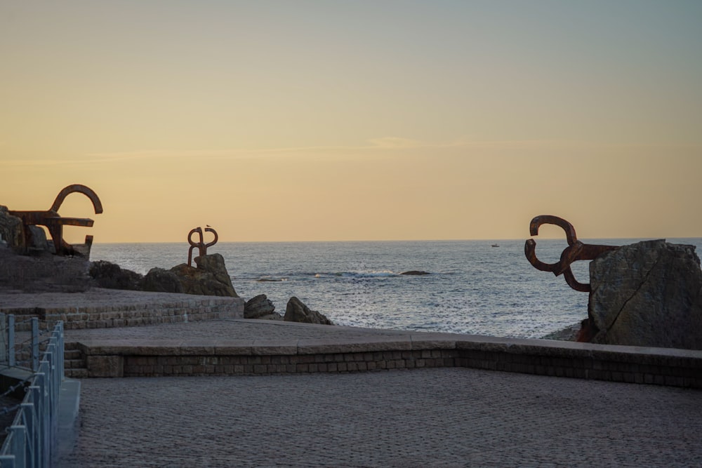 a couple of metal sculptures sitting on top of a beach