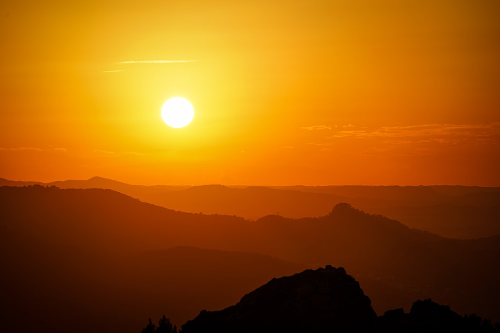 the sun is setting over a mountain range