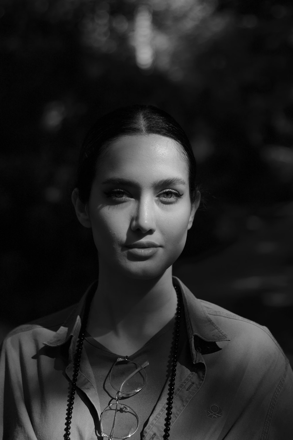 a black and white photo of a woman wearing a necklace