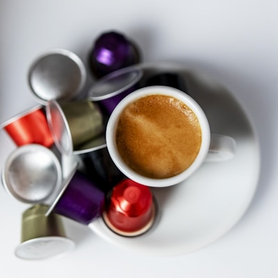 Stacked Ese pods ready for brewing, with a steaming cup of espresso nearby.