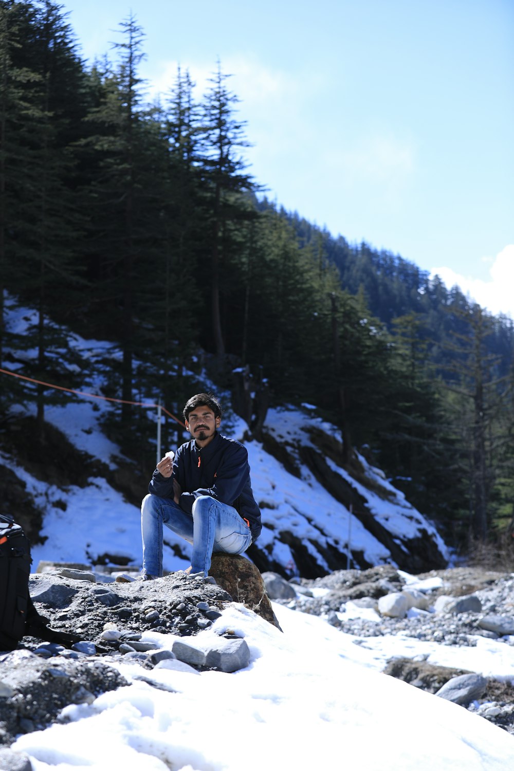 a man sitting on a rock in the snow