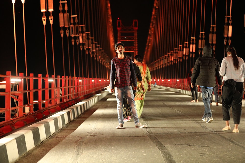 a group of people walking across a bridge at night