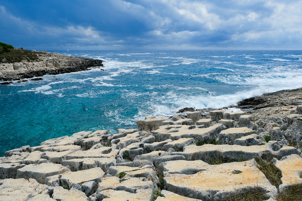 a view of a rocky beach with a body of water in the background