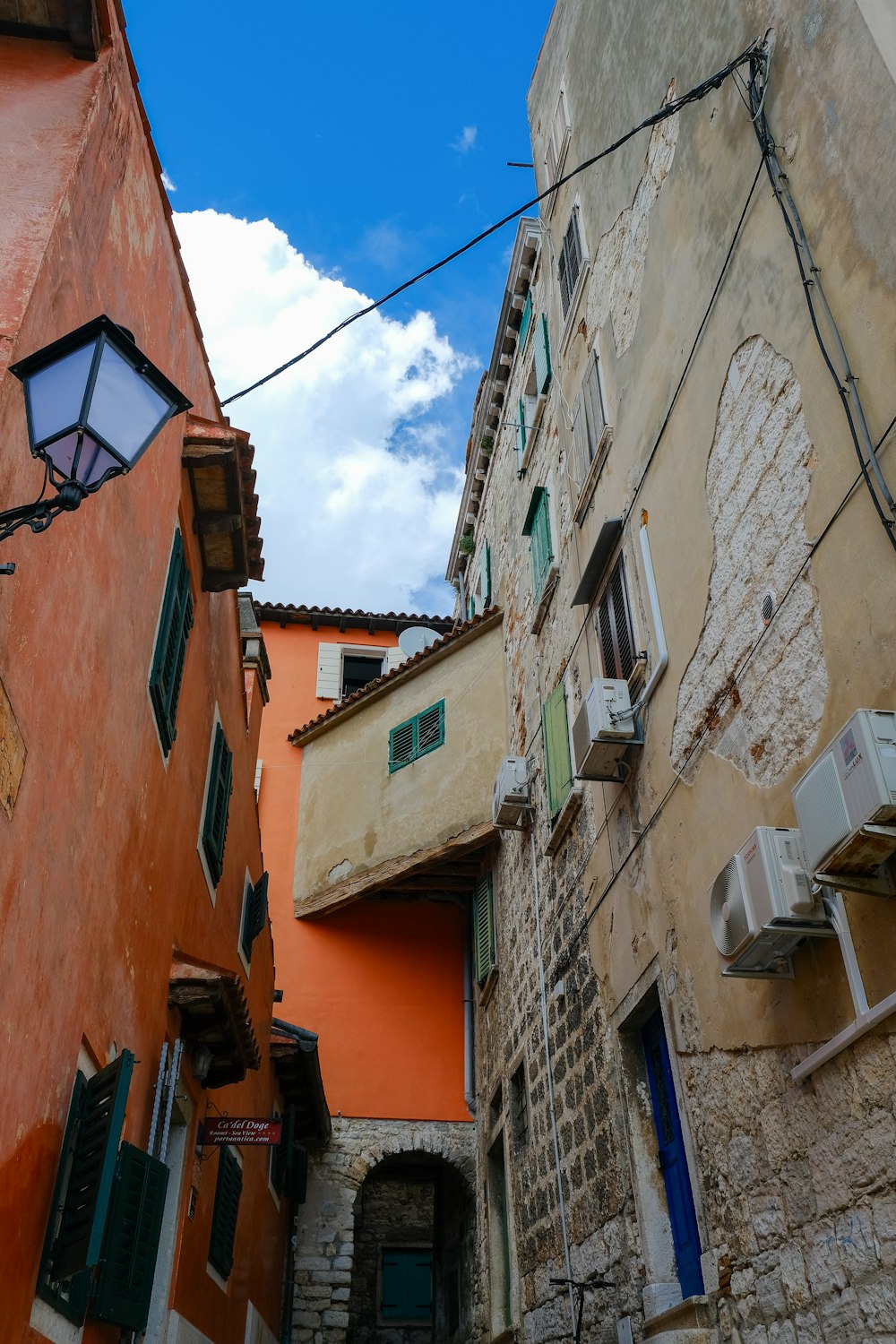 a narrow alleyway between two buildings with green shutters