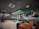 A modern, stylish restaurant interior featuring wooden tables and teal chairs. The ceiling has an array of hanging lights and decorations, with large windows offering a view outside. The ambiance is cozy yet contemporary, with patterned flooring adding a touch of elegance.