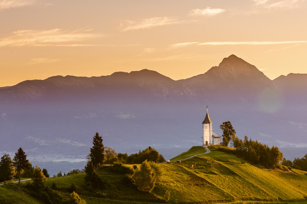 Una piccola chiesa su una collina erbosa con le montagne sullo sfondo