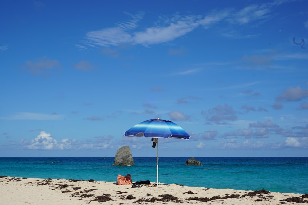 a blue umbrella sitting on top of a sandy beach