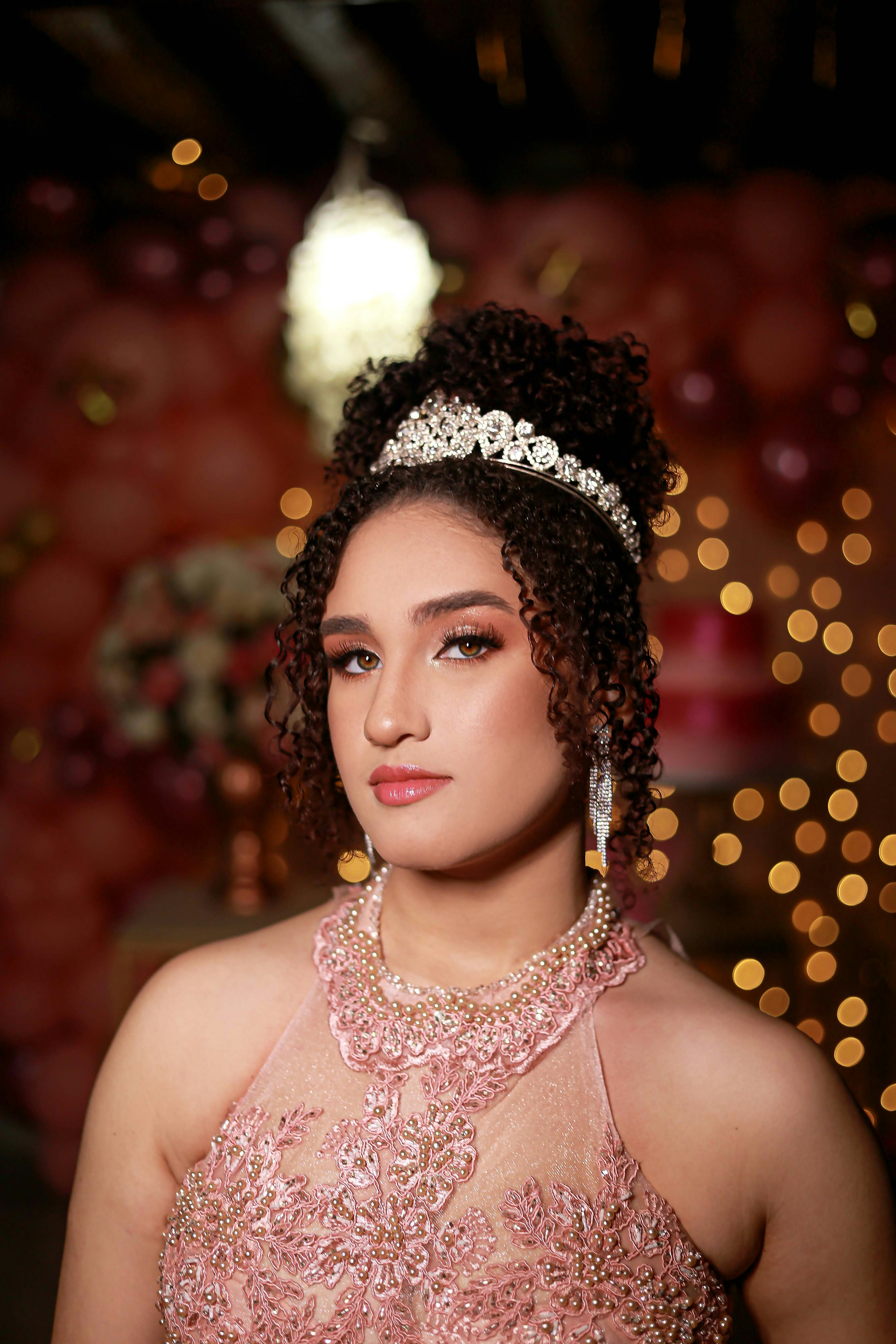 An artistic shot of a quinceañera in a stunning dress, surrounded by vibrant decorations and smiling guests.