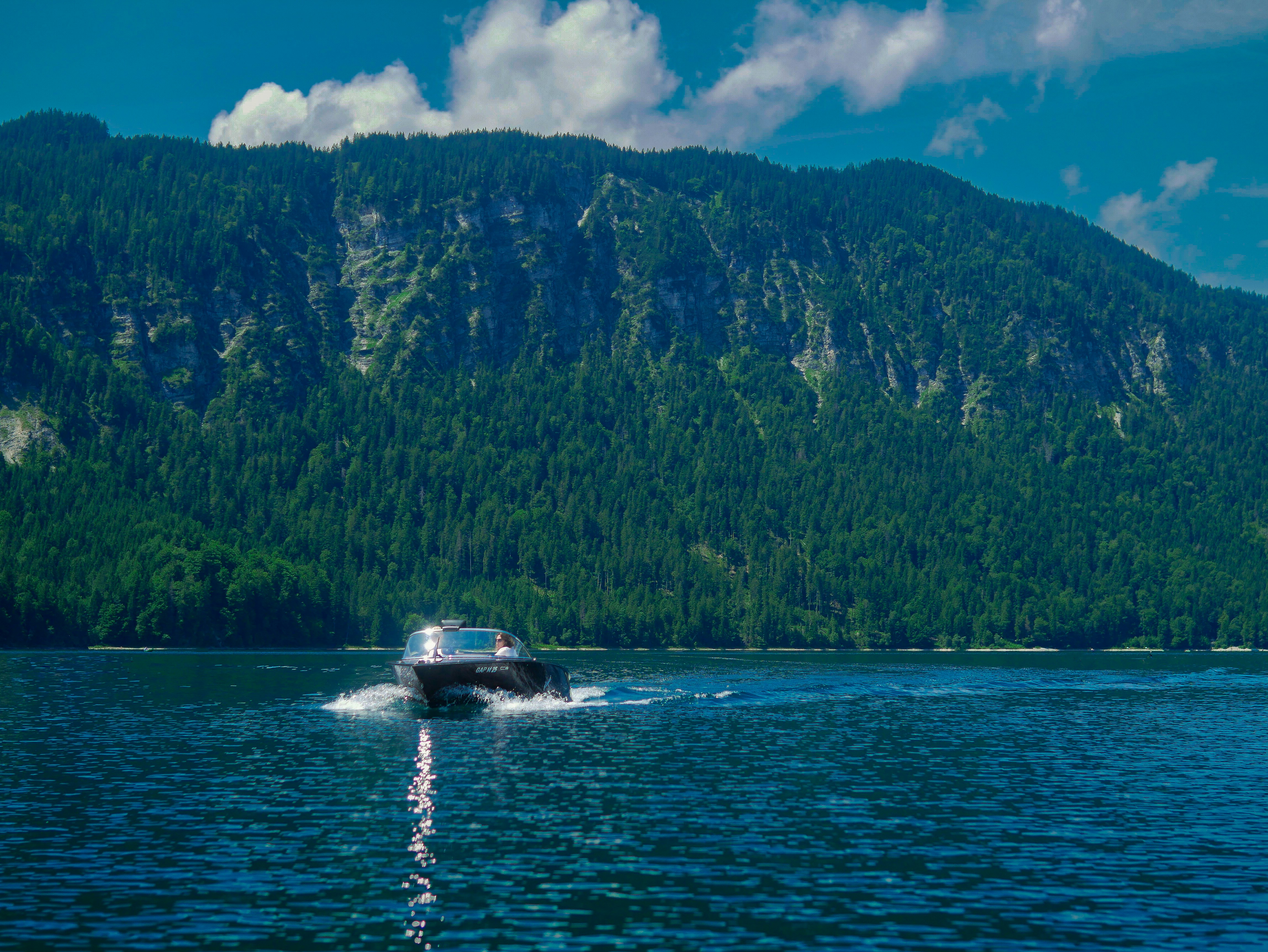a boat traveling on a lake near a mountain