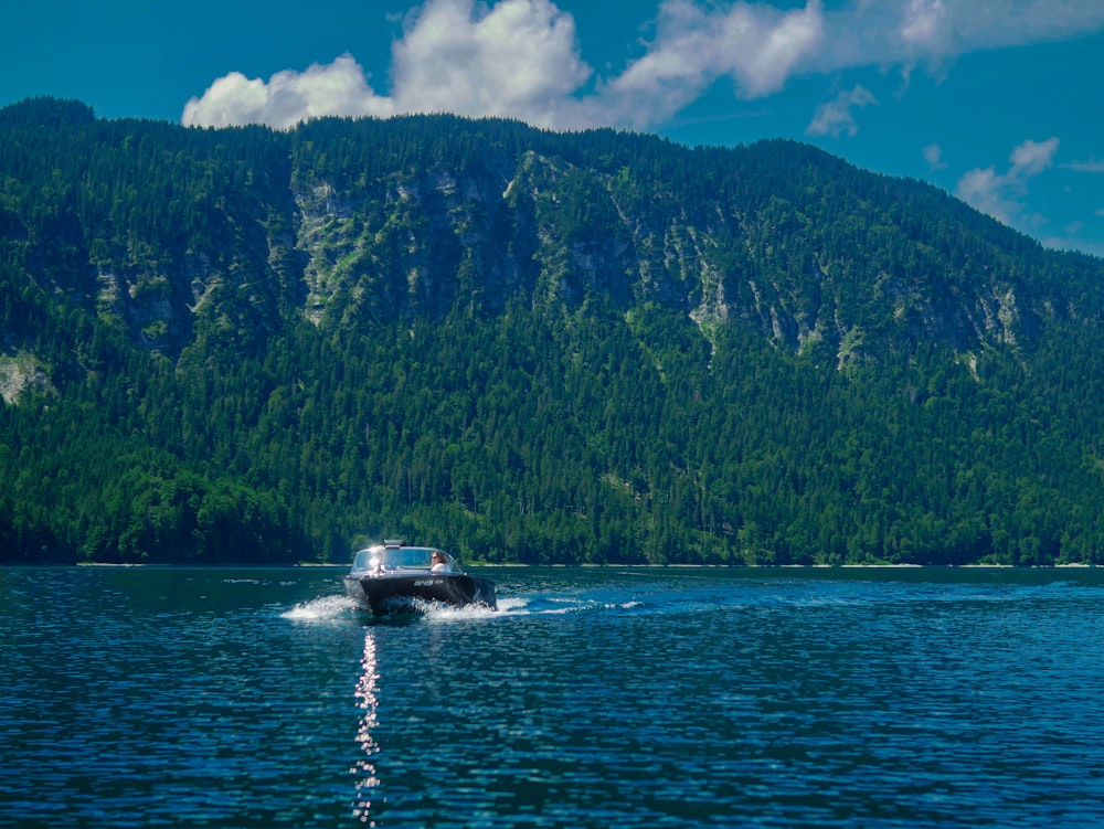 a boat traveling on a lake near a mountain