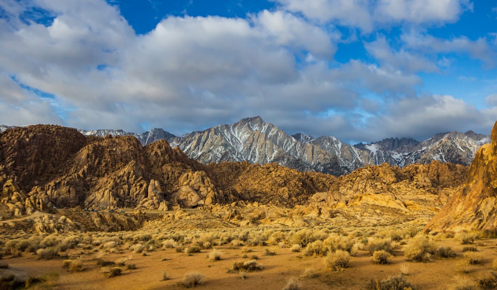 a desert with mountains and clouds in the background