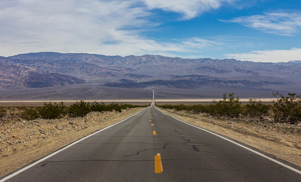 an empty road with mountains in the background