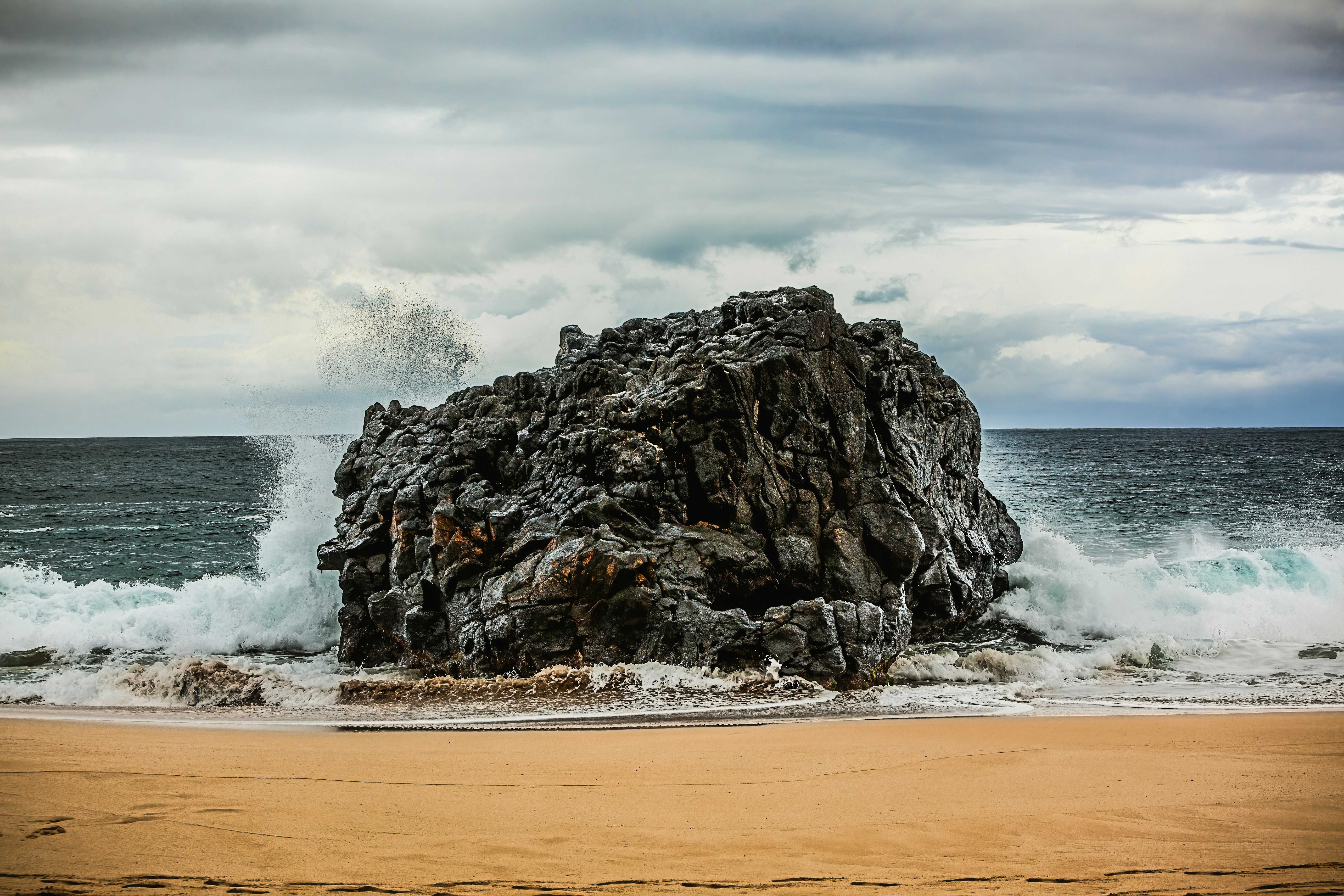 a large rock sitting on top of a sandy beach