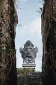 a large statue of a lion is seen through some rocks