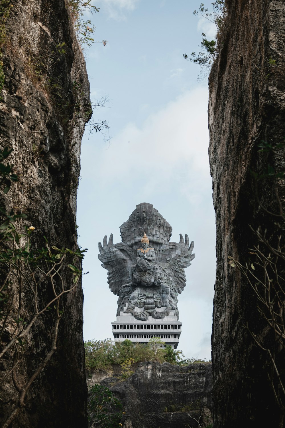 a large statue of a lion is seen through some rocks