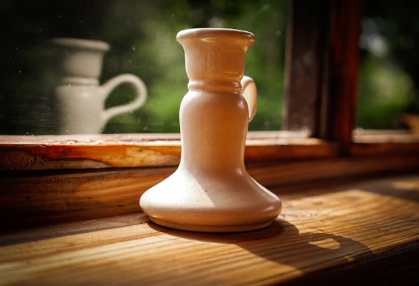 Elegant ceramic candle holders with natural beige and white tones displayed on a shelf
