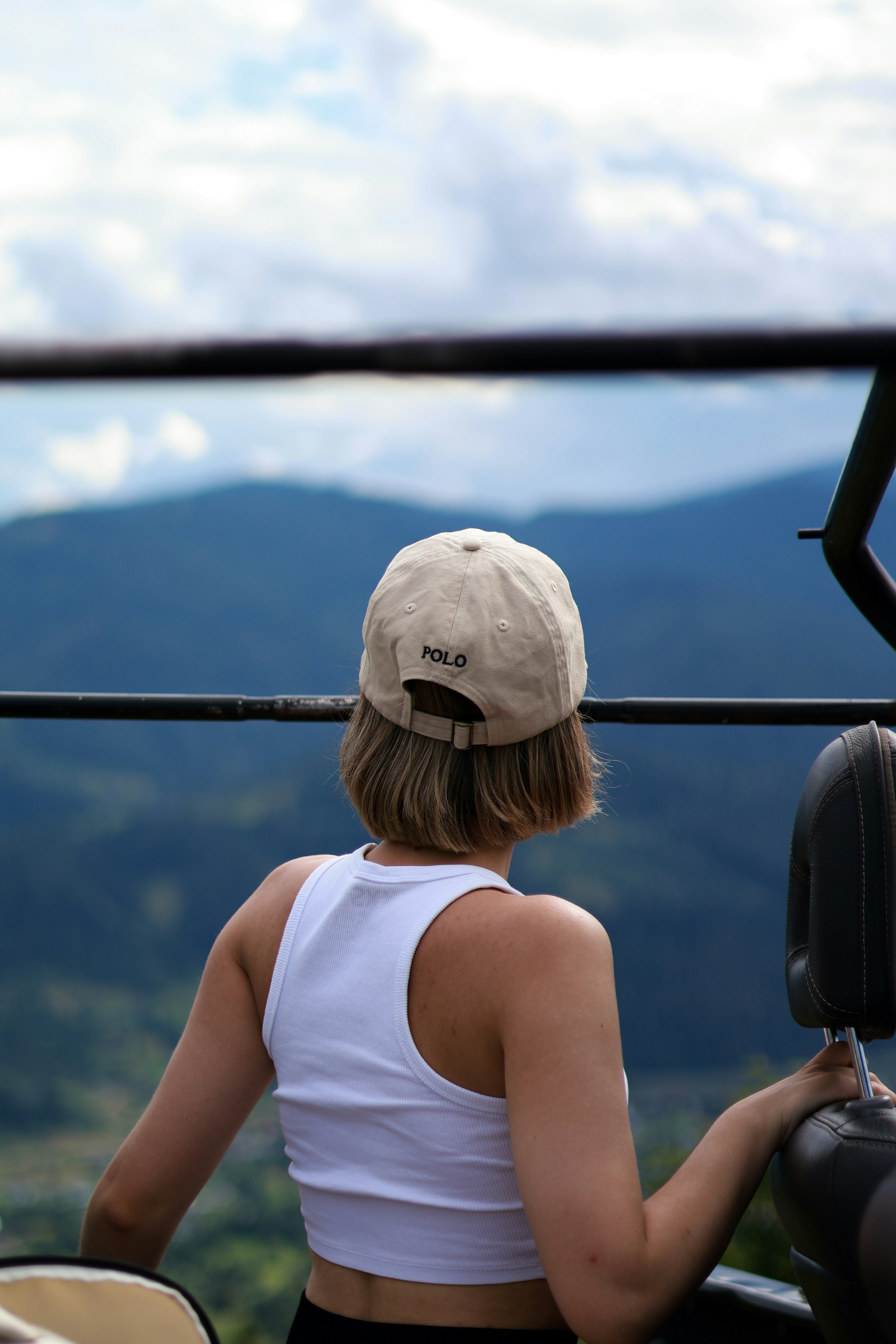a woman in a white tank top and a tan hat