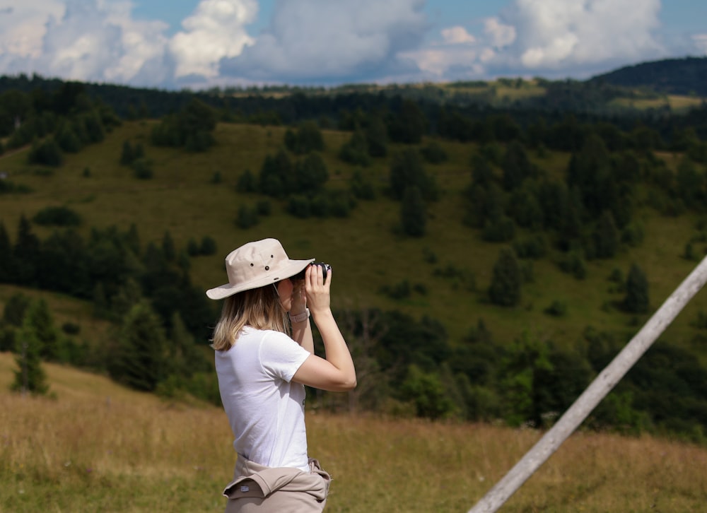 a woman standing in a field looking through a pair of binoculars