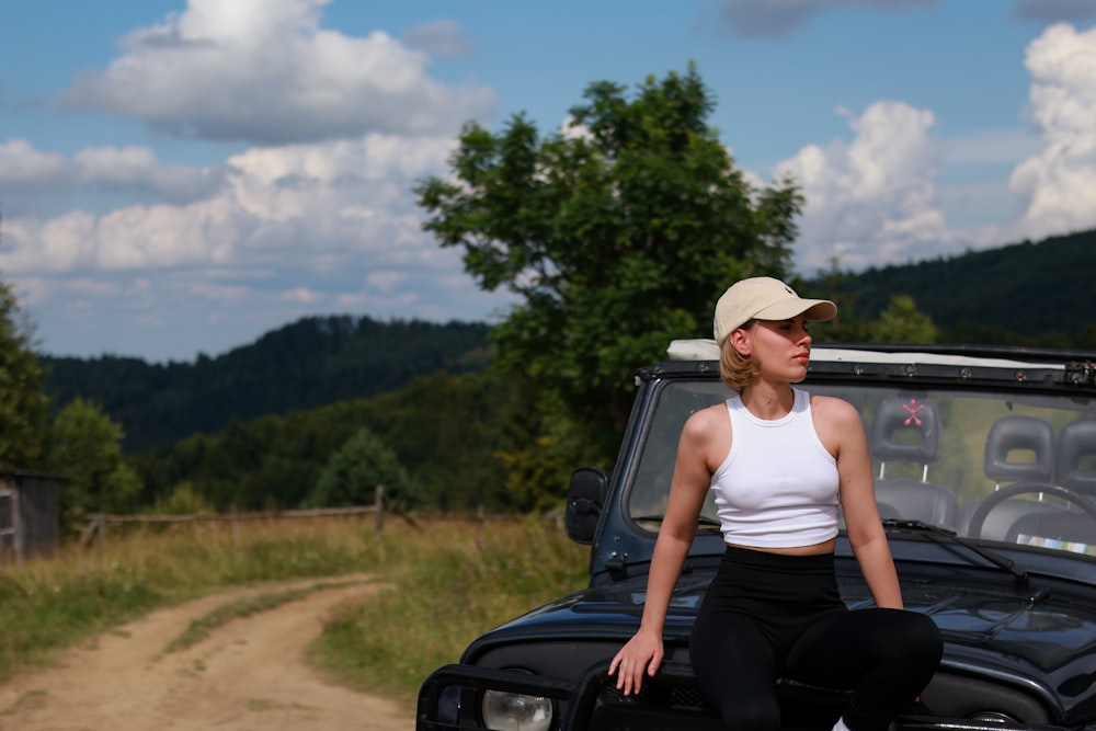 a woman sitting on the hood of a car