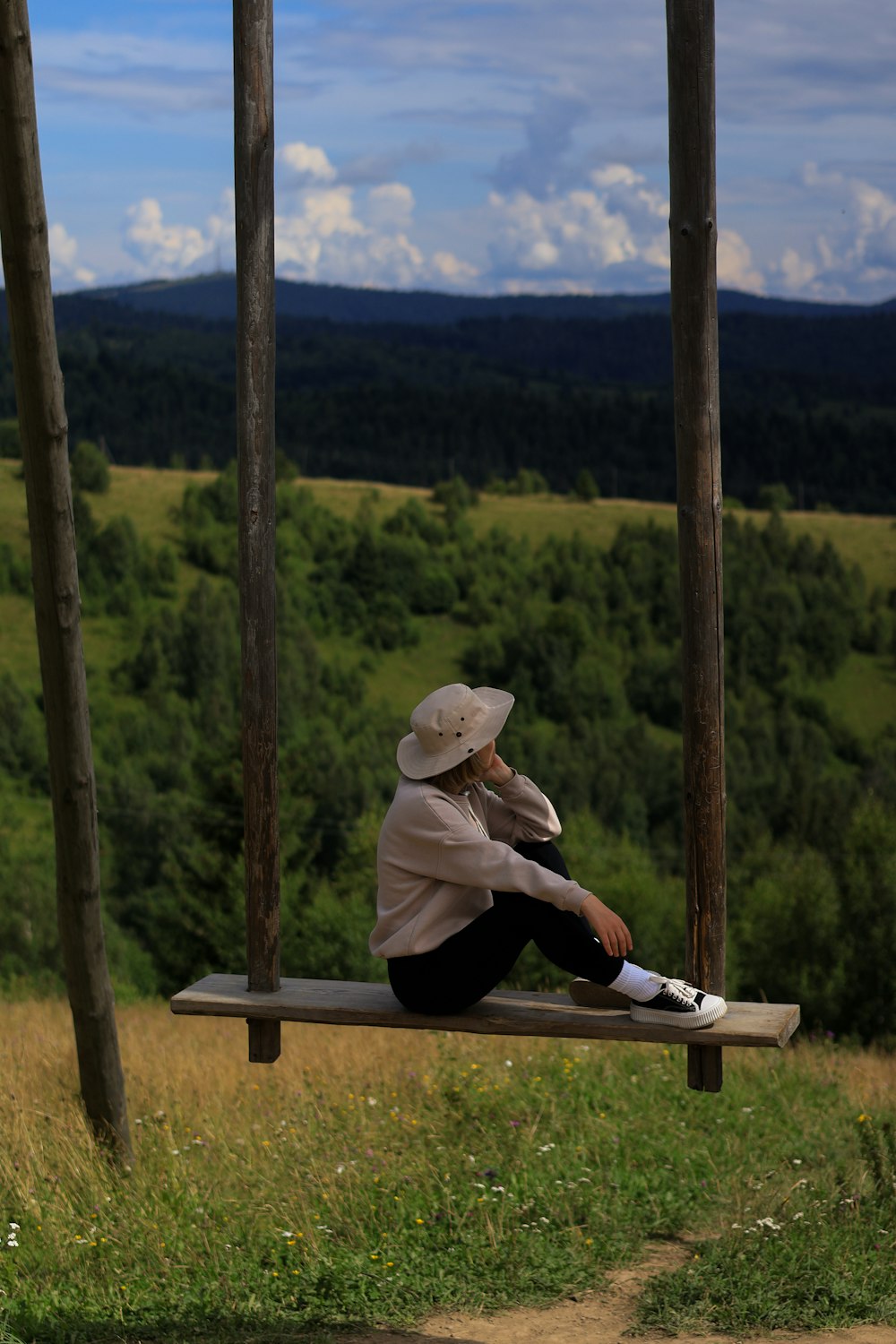 a person sitting on a wooden bench in a field