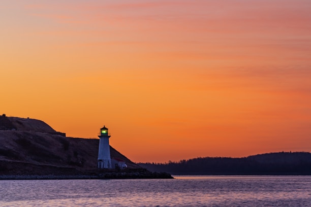 A serene lighthouse shining over calm blue waters at dawn, symbolizing guidance and security.