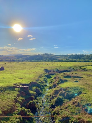 A smiling sun shining over rolling hills.
