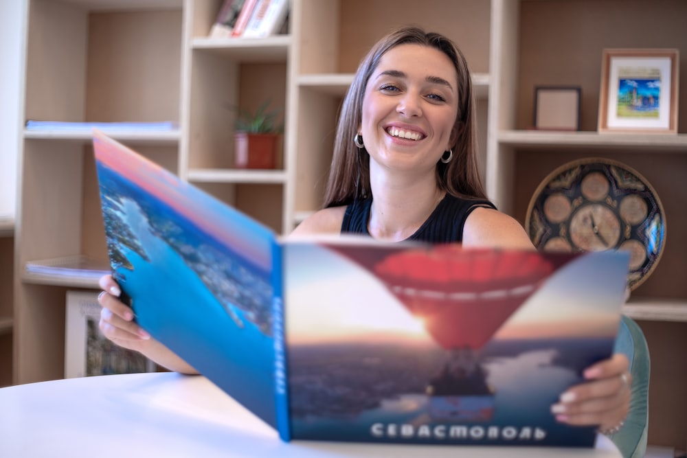 a woman sitting at a table with a book in front of her