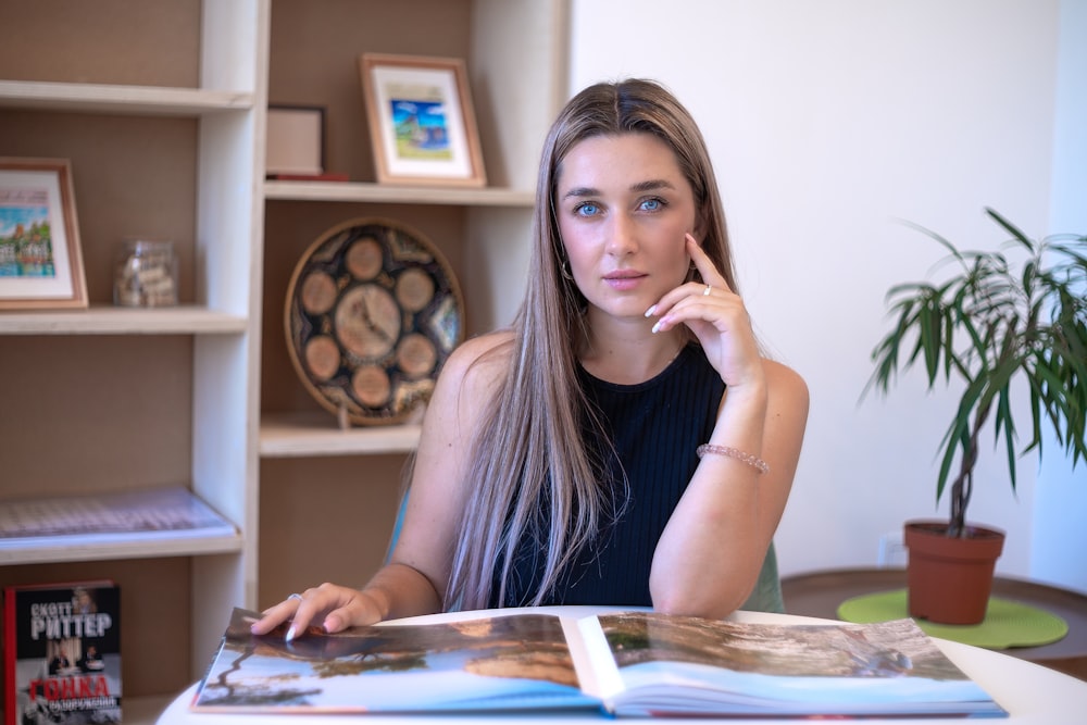 a woman sitting at a table with a book in front of her