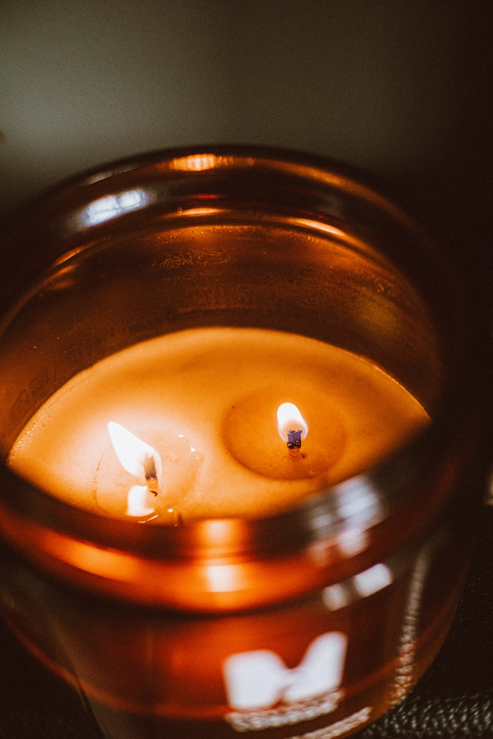 two lit candles in a glass bowl on a table